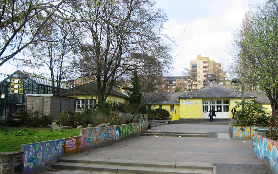 A paved, wide path leads to the entrance of the Statthaus Böcklerpark.