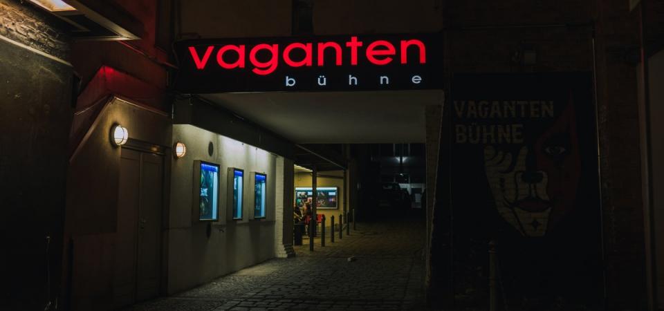 © Oana Popa Auf dem Foto ist der Zugang zur Vaganten Bühne bei Nacht zu sehen. Über dem Durchgang des Hinterhofs leuchtet der Vaganten-Schriftzug in roten Buchstaben.